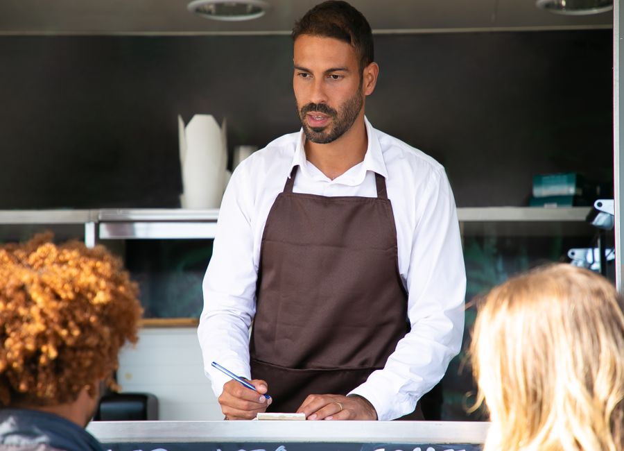 A business owner taking an order at his counter